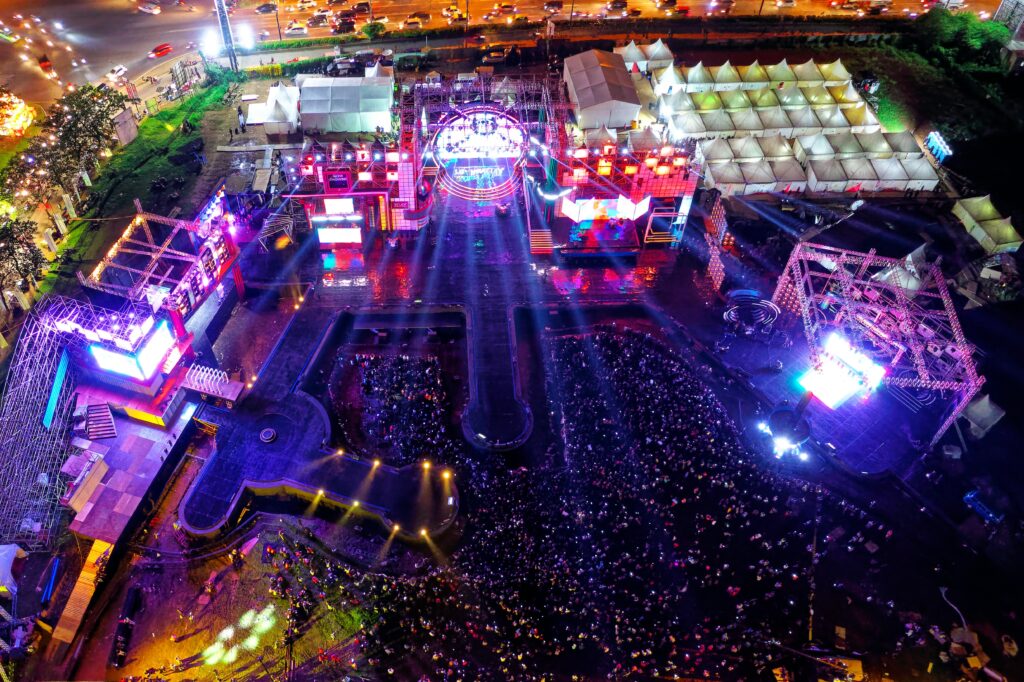 Aerial view of a vibrant music festival in Serpong, Indonesia with crowds and stage lights.