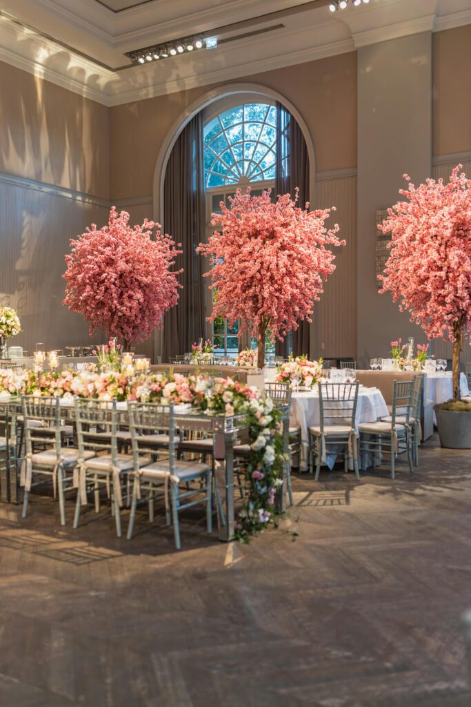 Sophisticated indoor wedding venue with stunning cherry blossoms and chic table arrangements.