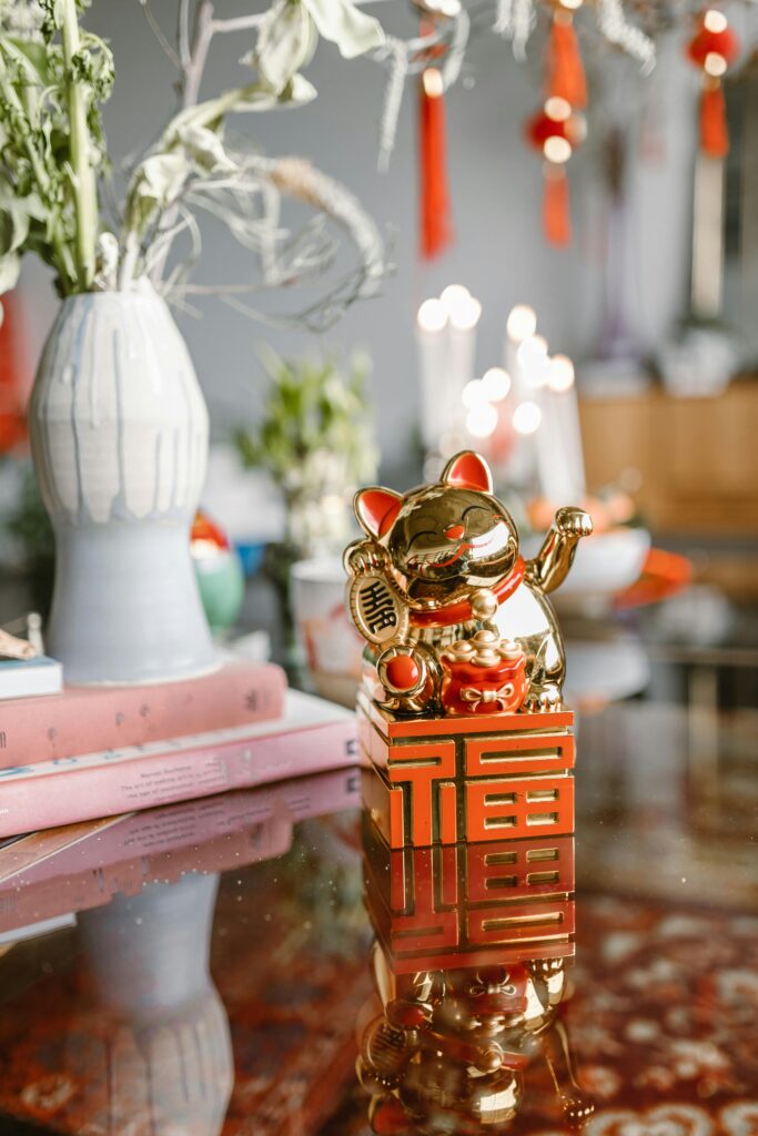 Golden Maneki Neko figurine on table with festive decor and plants, perfect for celebrations.